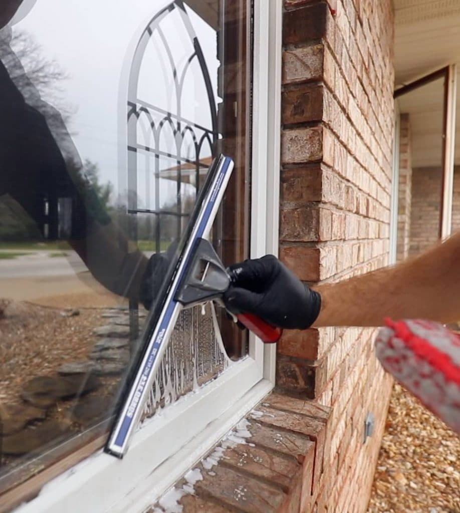 Hand using a squeegee to clean a window