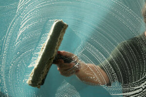 Using a wet, soapy rag to clean a window pane